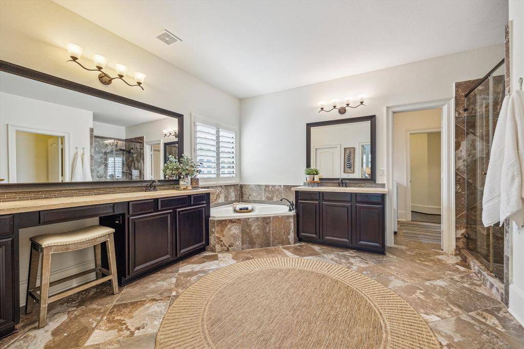 This luxurious ensuite is as functional as it is beautiful, featuring gorgeous tile throughout and two separate granite vanities, each with ample storage, framed mirrors, and stylish vanity lighting. A relaxing soaking tub and separate walk-in shower complete the space, offering the perfect blend of comfort and elegance. Additionally, the laundry/utility room can be accessed from the door pictured to the right.