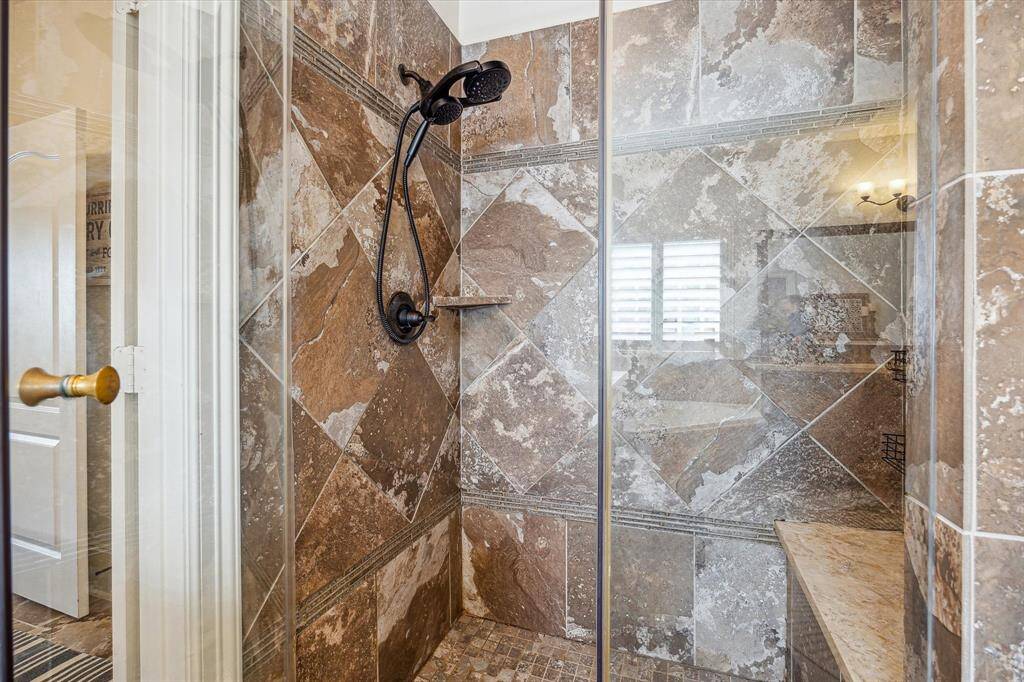 This convenient walk-in shower features upgraded fixtures, a built-in bench for added comfort, and sleek frameless glass.