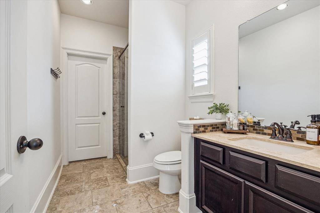 This first-floor ensuite bathroom features a sleek single sink vanity and a fully tiled walk-in shower with frameless glass, combining style and convenience for your guests’ comfort.