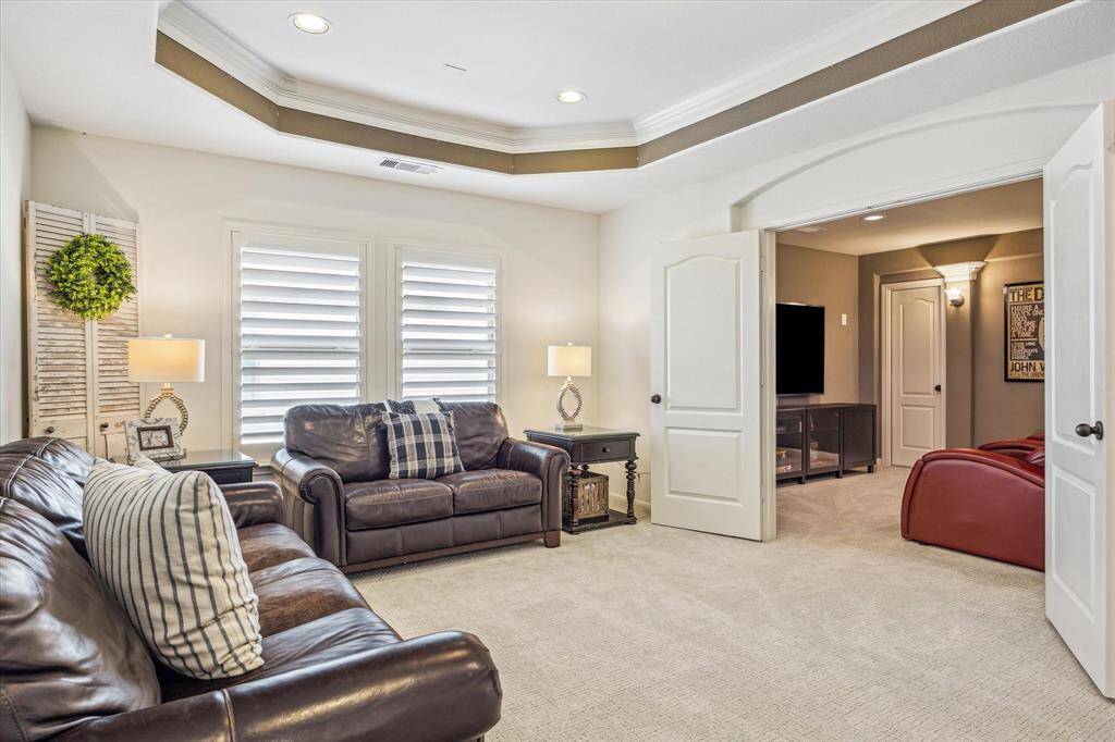 This spacious game room is the perfect hangout spot for family and friends, featuring a tray ceiling, recessed lighting, and plenty of room to relax or play. Double doors lead to the adjoining media room, ideal for movie nights, gaming marathons, or watching the big game in comfort and style.