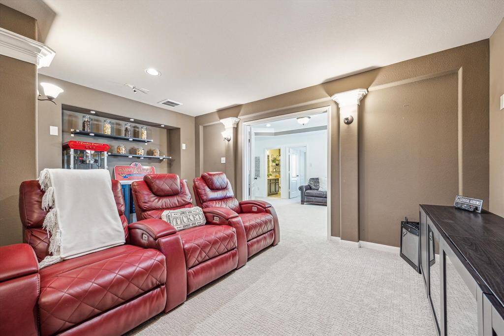 Step into the media room, your private escape for cinematic experiences and game-day excitement. This cozy space features plush carpeting, ambient sconce lighting, and room for theater seating. A built-in area for snacks or equipment makes it as functional as it is fun.