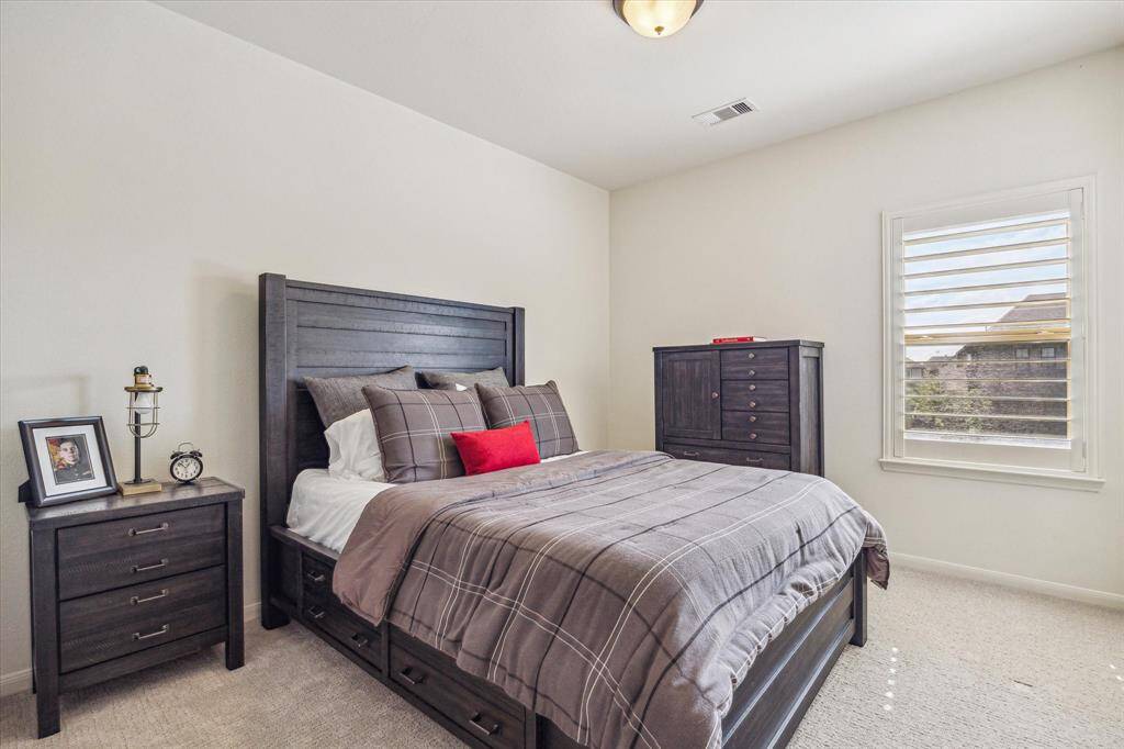 Another inviting upstairs suite features soft neutral carpet and paint, wood-shuttered windows, a spacious walk-in closet, and private ensuite access to a full bathroom.