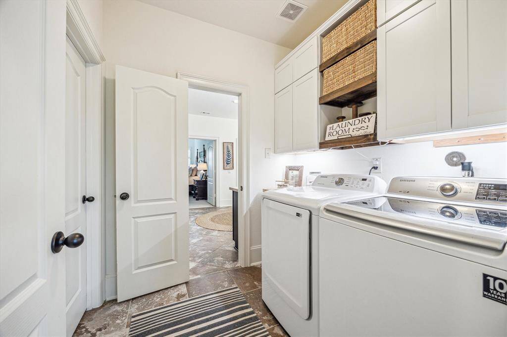 The utility room is conveniently accessible from the owner's bathroom and a hallway. It offers tile flooring, built-in cabinetry for household storge, under-cabinet lights, and both gas and electric dryer connections.