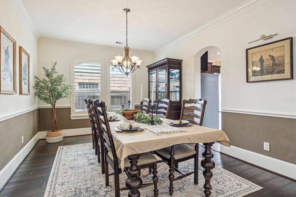 This elegant formal dining room sets the perfect stage for celebrating every occasion. It features hardwood flooring, designer paint, chair and crown molding, wood-shuttered windows, a stylish chandelier, and ample space for your banquet table and sideboard.
