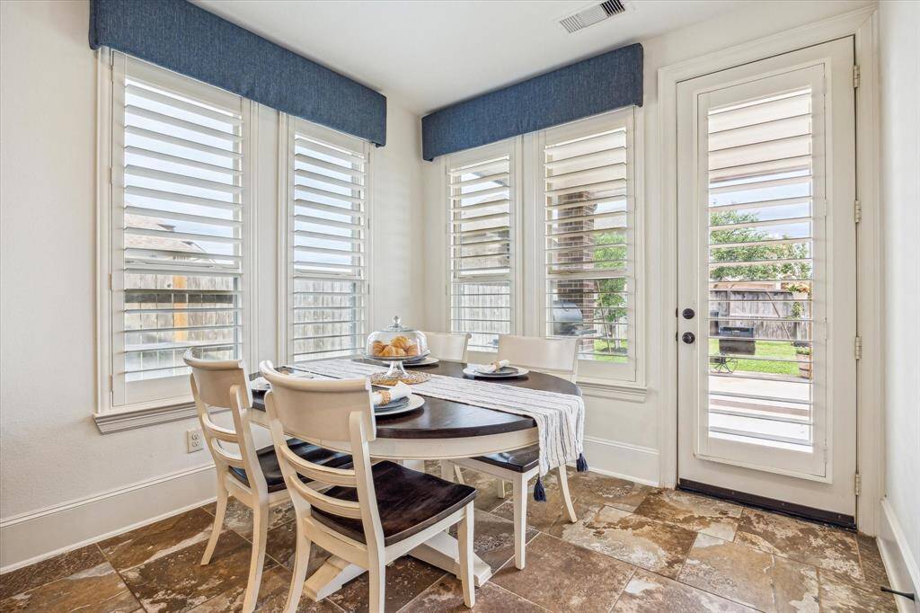 Enjoy delicious meals and lively conversation in the charming breakfast area, featuring beautiful tile flooring and wood-shuttered windows that fill the space with natural light.