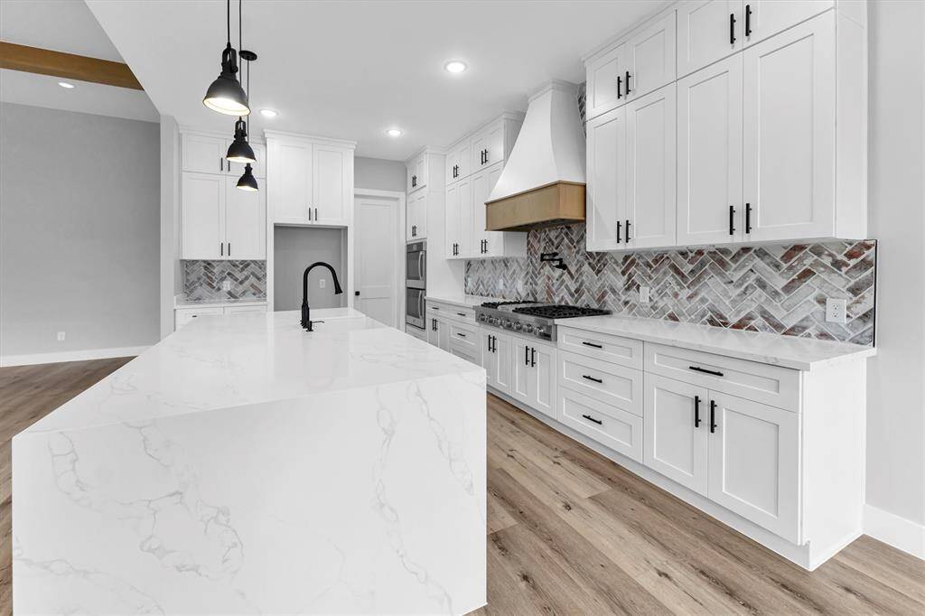 The stylish kitchen is a chef's dream, boasting high-end stainless appliances, including a double wall oven, a deep sink, soft-closing drawers and cabinets, a 48” gas burner range, a pot filler, quartz countertops, an oversized island, and a large pantry. This space is designed for both functionality and elegance, making meal preparation a delight