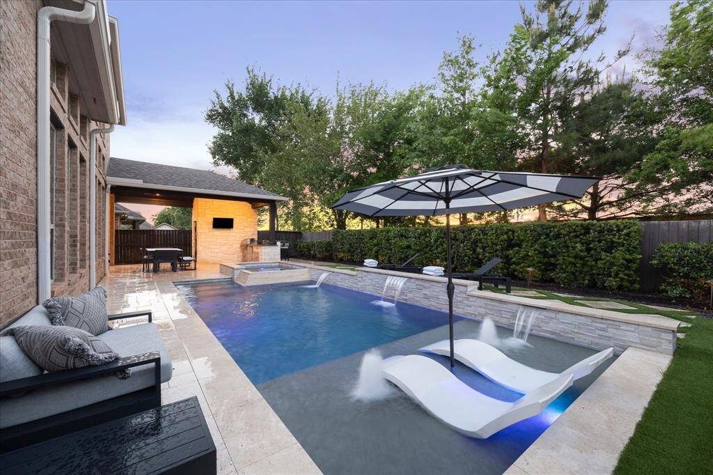 Built by Regal Pools, this Awe-inspiring Backyard Oasis Boasts a Modern Linear Style Pool with In-Floor Cleaning System, Fountains, Sheer Descents, Sun Deck, Travertine Coping & Pavers, Stack Stone Raised Wall and Relaxing Spillover Spa!