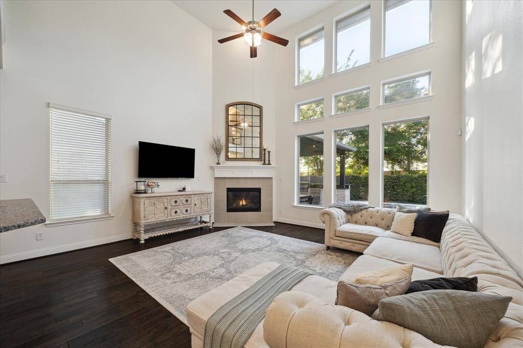 Spacious Family Room with High Ceiling, Gas Log Fireplace, Ceiling Fan, and Wall of Windows Overlooking Your Backyard Oasis