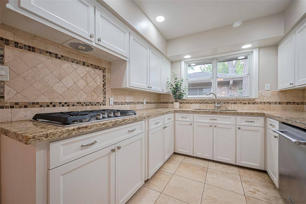 Tile backsplash, Travertine Tile floor and granite countertops grace this kitchen.