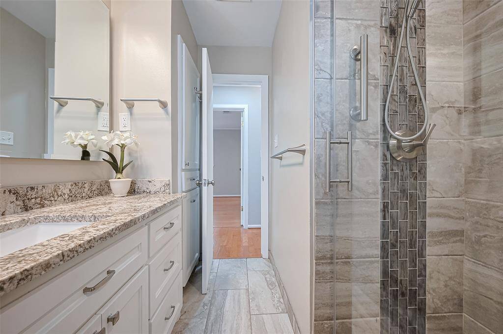 Updated hall bath features tile floors, walk in glass door shower and granite countertops.