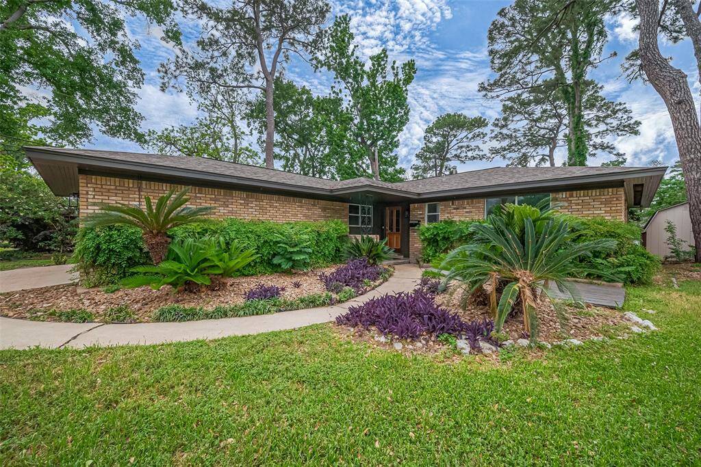 Love the lines of this brick Ranch Style home with Mature trees all Around it. Love the greenery.