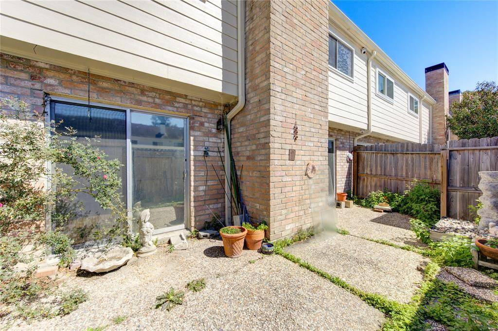 A photo of the charming backyard patio area with brick and siding exterior, featuring a sliding glass door