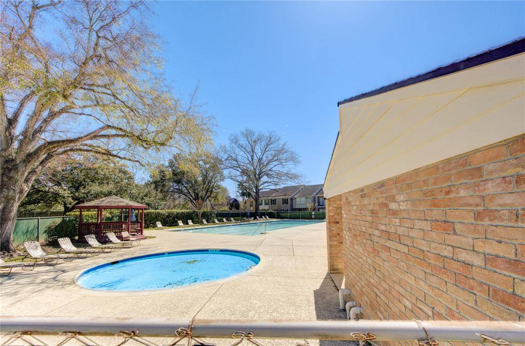 The spacious outdoor pool area with a smaller circular pool, surrounded by lounge chairs and a gazebo with trees providing a natural backdrop and creating a serene setting for relaxation.