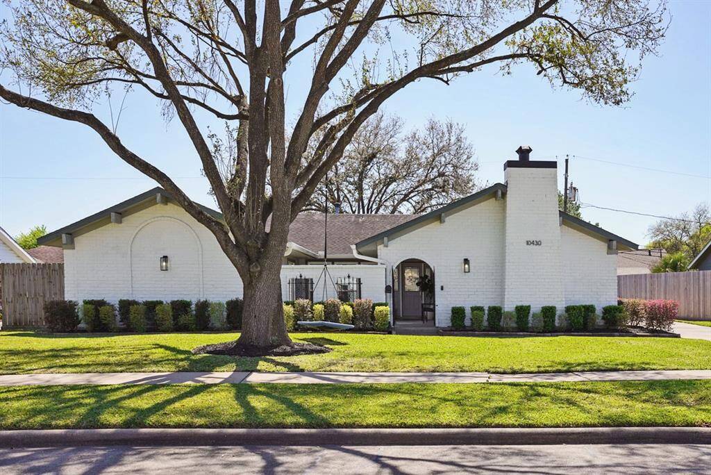 Front Exterior – Stunning white brick home with mature trees and a charming courtyard entry.