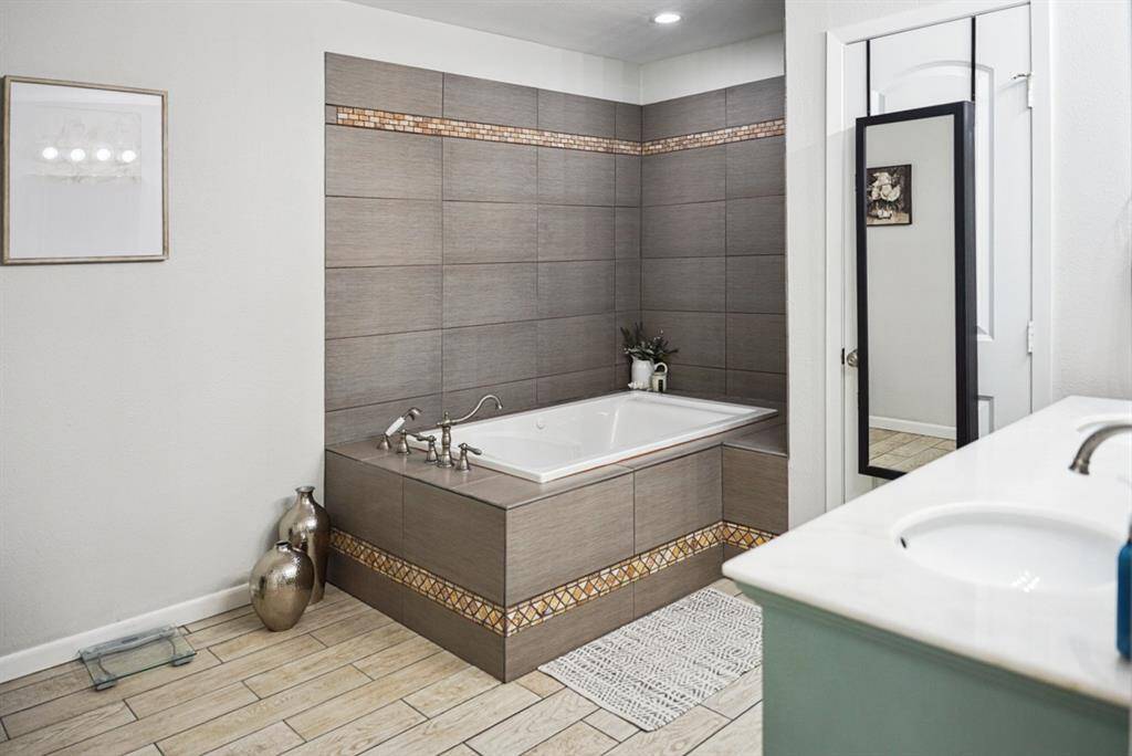 Primary Bathroom – Elegant soaking tub with decorative tile accents for a spa-like feel.