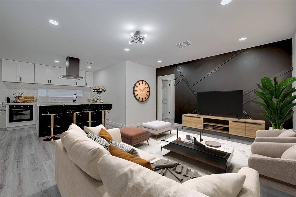 The living room is a striking yet inviting space that seamlessly connects to the open-concept kitchen, creating an expansive area perfect for relaxation and entertaining.