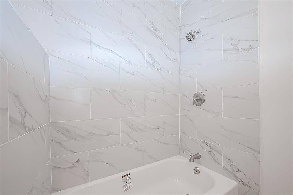 The sleek, white tiles enhance the clean, modern aesthetic while contributing to the bright and refreshing feel of the space. A thoughtfully designed shower-tub combo offers versatility and comfort, providing the perfect space to unwind after a long day.