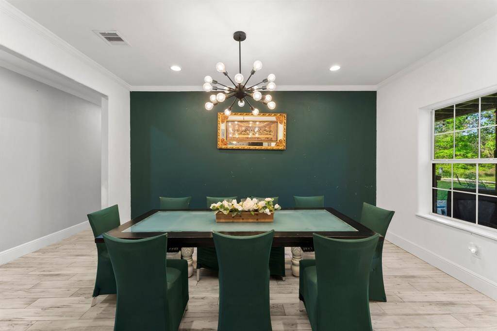 This modern dining room offers a sophisticated ambiance with its bold accent wall and contemporary lighting fixture. The well-defined space is ideal for both intimate dinners and larger celebrations.
