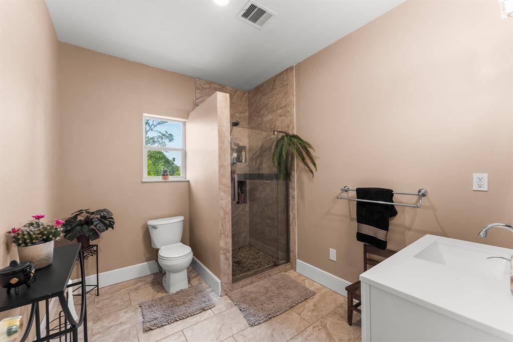 This bathroom features a convenient and spacious walk-in shower with attractive tile work. The functional layout also includes a comfortable vanity and good natural light from the window.