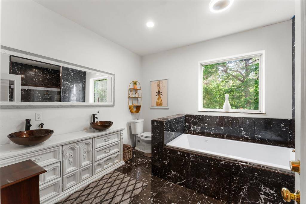 The elegant design of this bathroom is enhanced by natural light streaming through the window. Enjoy the luxury of a soaking tub and the convenience of double vanities with sophisticated vessel sinks.