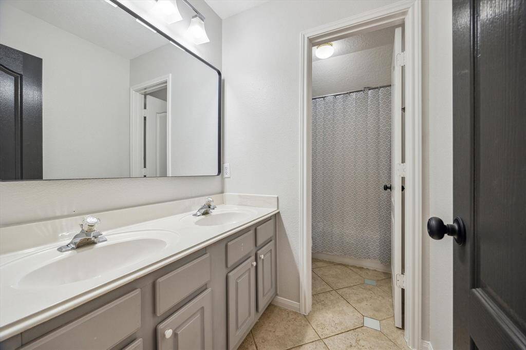 Secondary bathroom with travertine flooring and dual sinks!