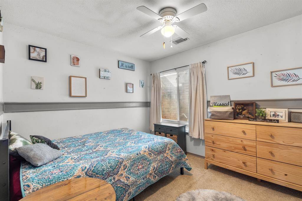 A stylish second bedroom featuring a comfortable queen bed, tastefully adorned with fresh, modern accents. The room boasts clean lines, soft neutral tones, and a touch of contemporary decor, creating a serene and inviting space perfect for rest and relaxation.