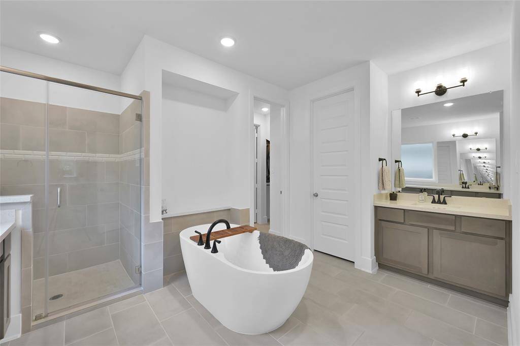 Primary bathroom offers two vanity areas with sinks, stand alone soaking tub, TEXAS-sized walk in shower, and not one but TWO walk-in closets.