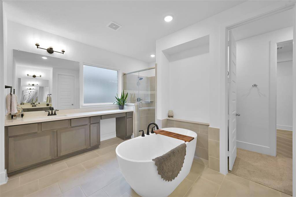 Primary bathroom offers two vanity areas with sinks, stand alone soaking tub, TEXAS-sized walk in shower, and not one but TWO walk-in closets.