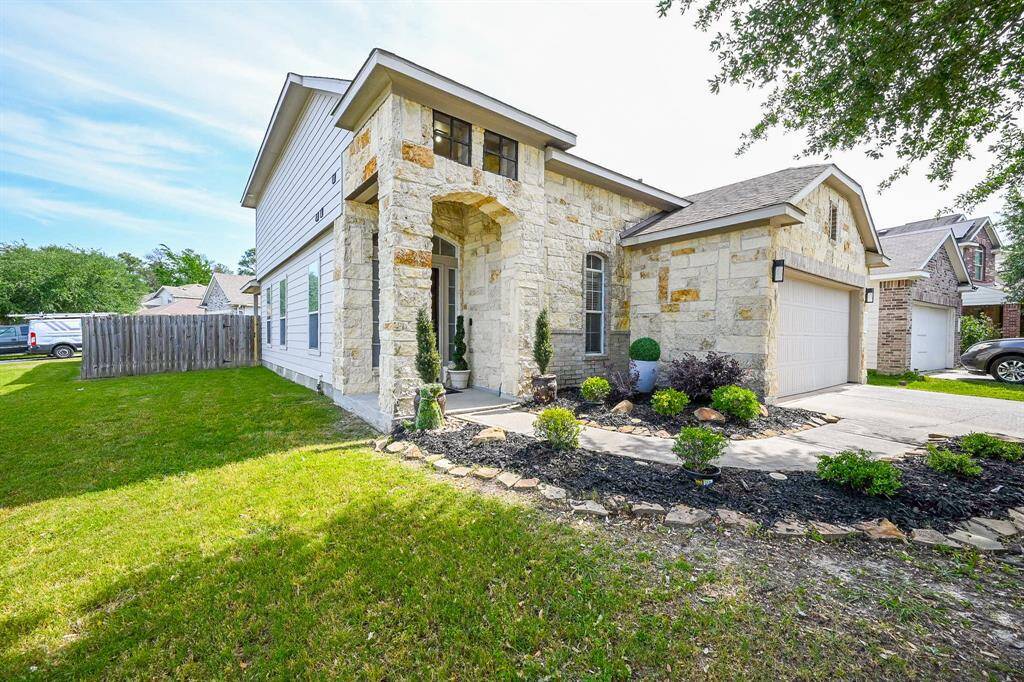 It boasts a striking stone and brick exterior with an inviting covered front porch.