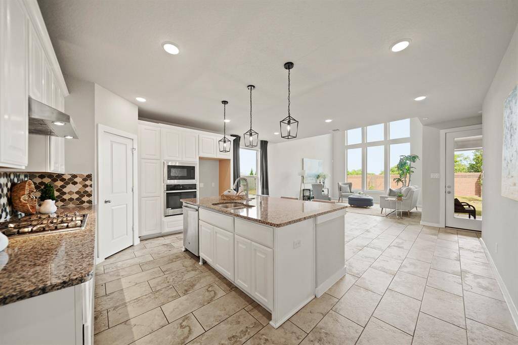 Open. Bright. Effortless.This stunning kitchen features crisp white cabinetry, elegant lighting, and a central island that connects seamlessly to the oversized living area. Glass doors invite you to the covered patio and backyard, creating a perfect indoor-outdoor flow for relaxed living or stylish entertaining.