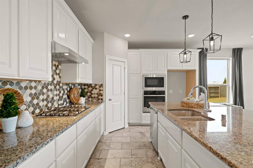 Crisp. Clean. Elevated.Beautiful countertops and classic white cabinetry set a refined tone, while built-in microwave and oven appliances add a sleek, modern touch. This kitchen delivers the luxury of thoughtful design with everyday convenience.