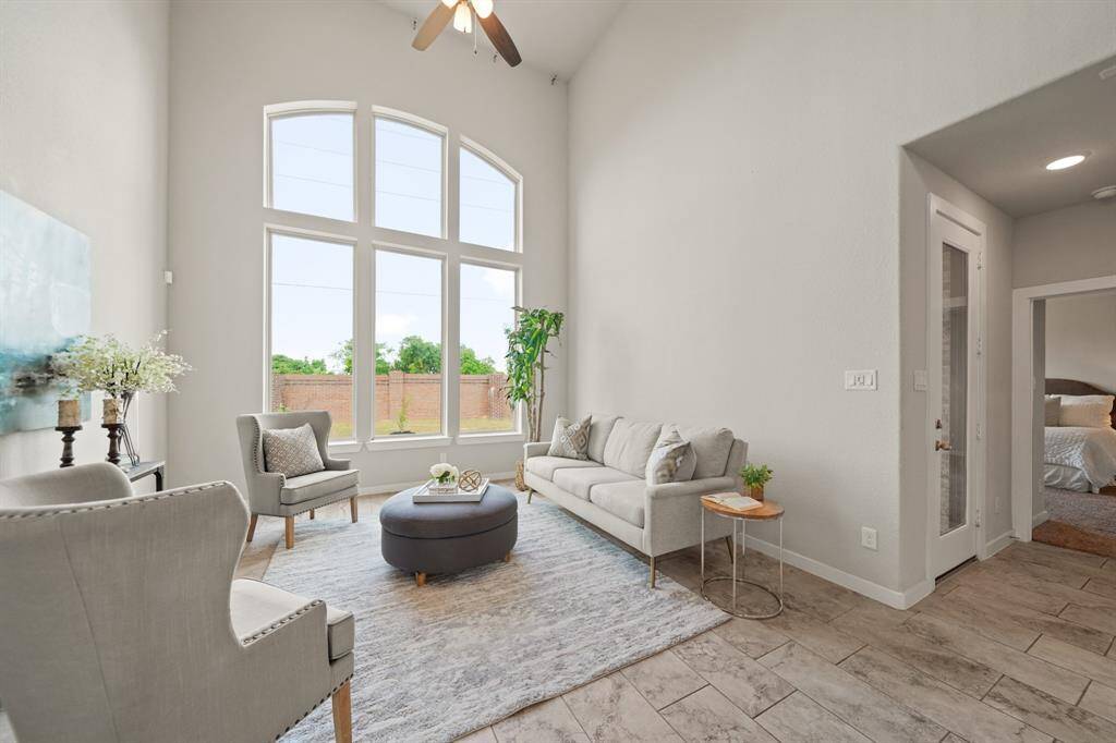 A Living Space that Opens Up.This expansive living room showcases high windows, filling the space with natural light and offering a breathtaking view of the backyard, complete with a brick fence and no rear neighbors. Beyond the light-filled space, glimpses of the entry and the primary bedroom add a touch of privacy and comfort, creating an ideal balance of openness and seclusion.