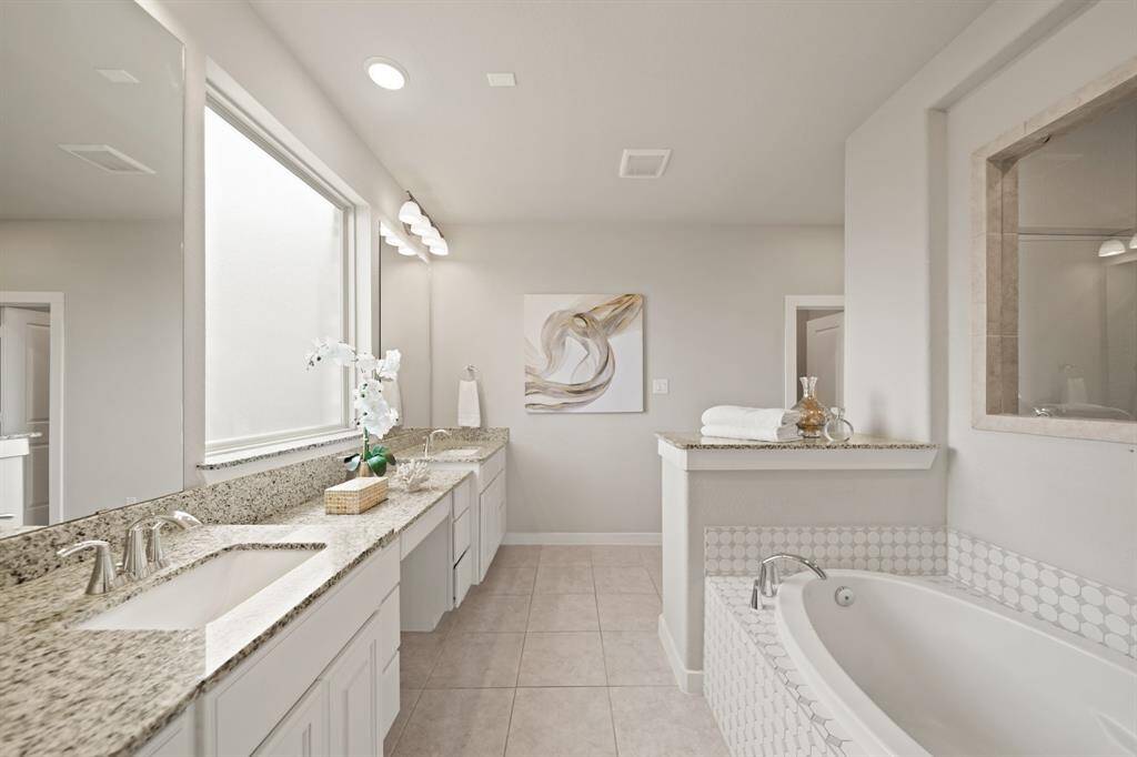 Open, Airy, and Inviting.This bathroom offers a view of the entry to the spacious walk-in closet on the left and an open doorway to the primary bedroom on the right. Through the glass, you can catch a glimpse of the shower, seamlessly blending with the rest of the bathroom’s clean and airy design.