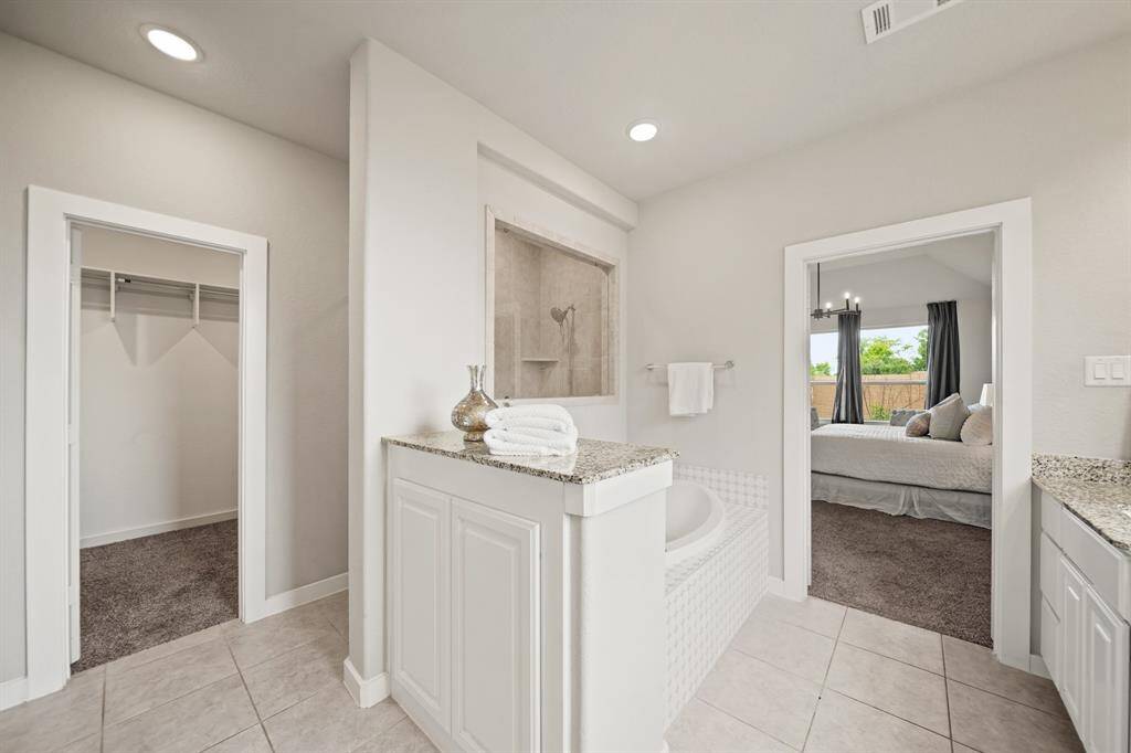 Elegant and Inviting.This view showcases the entry to the spacious shower and the white cabinetry vanity. The shower, though appearing compact in the photo, offers more room than it seems, providing both style and practicality in the design.
