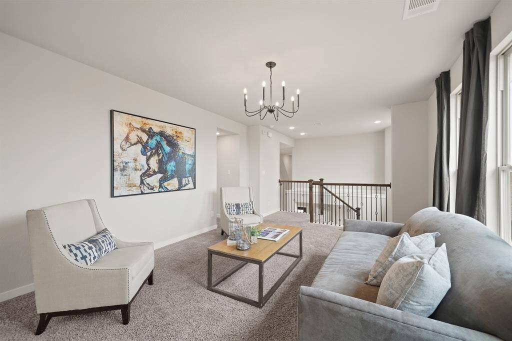 Stunning Views from Above.Looking down from the upstairs, this expansive view of the oversized living room opens up to long windows and a beautiful glimpse of the backyard. With no back neighbors and a brick fence, the space offers privacy and a serene, open feel.