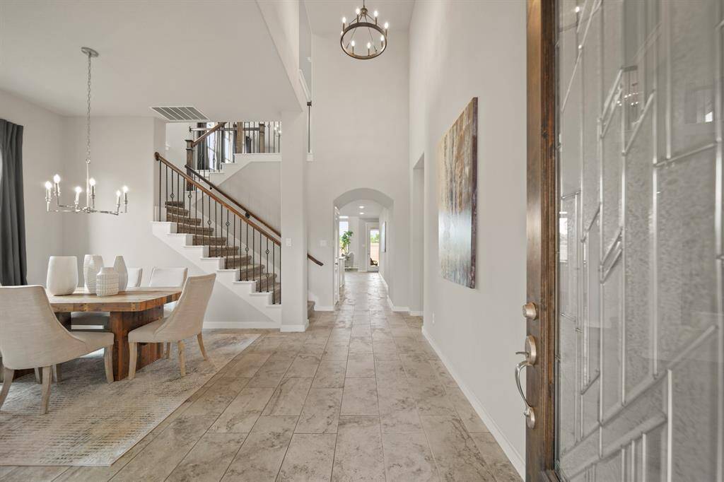 Where Light Leads and Style Follows.Step inside to an airy, light-filled entry framed by elevated ceilings and warm-toned floors. Formal dining welcomes to the ahead left, just ahead of the formal study not in this shot. The thoughtful layout draws your eye toward the inviting backyard beyond—subtle luxury at every turn.