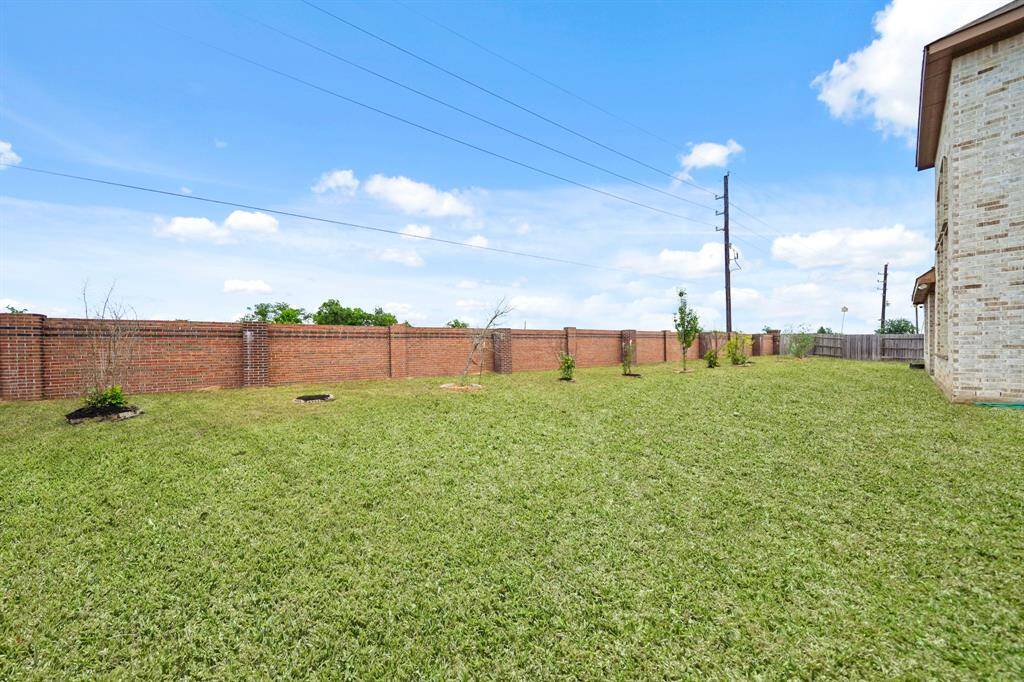 Another View of the Spacious Backyard.This angle showcases the large size of the backyard, offering plenty of room for outdoor activities. Notice the solid brick exterior and large windows that bring light and style to the home.