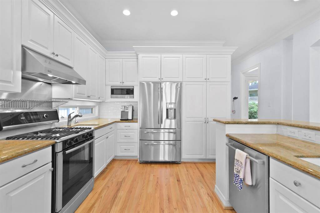 From the opposite side of the kitchen, there is the refrigerator, microwave and additional storage.