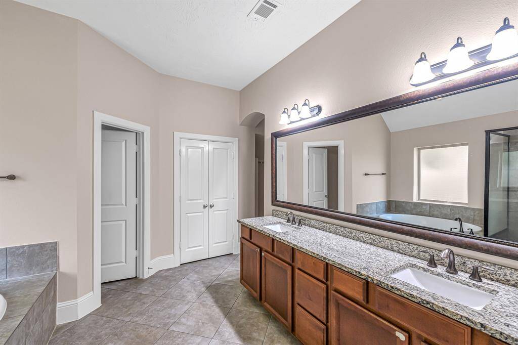 First primary bath features dual sink vanity, private water closet, and large linen closet with double doors.