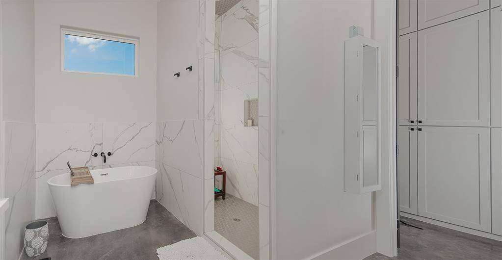 The primary ensuite has a soaking tub and walk-in shower/closet with custom built-ins for organization.