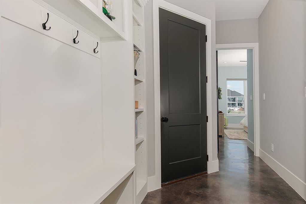 The hallway leading you to the secondary bedrooms includes a mud room with storage shelves and coat hangers.