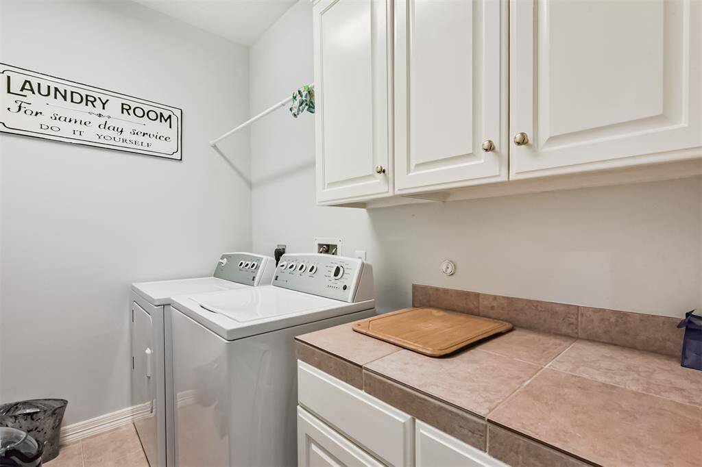 Utility room includes washer and dryer which stay with home, convenient folding area and ample storage for added functionality .
