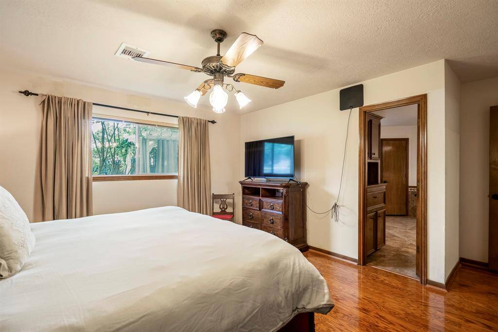 Primary Bedroom with wood floors and a ceiling fan