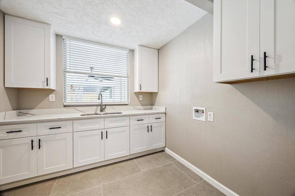 INDOOR LAUNDRY ROOM WITH FRESH CABINETS, SINK AND COUNTERTOPS