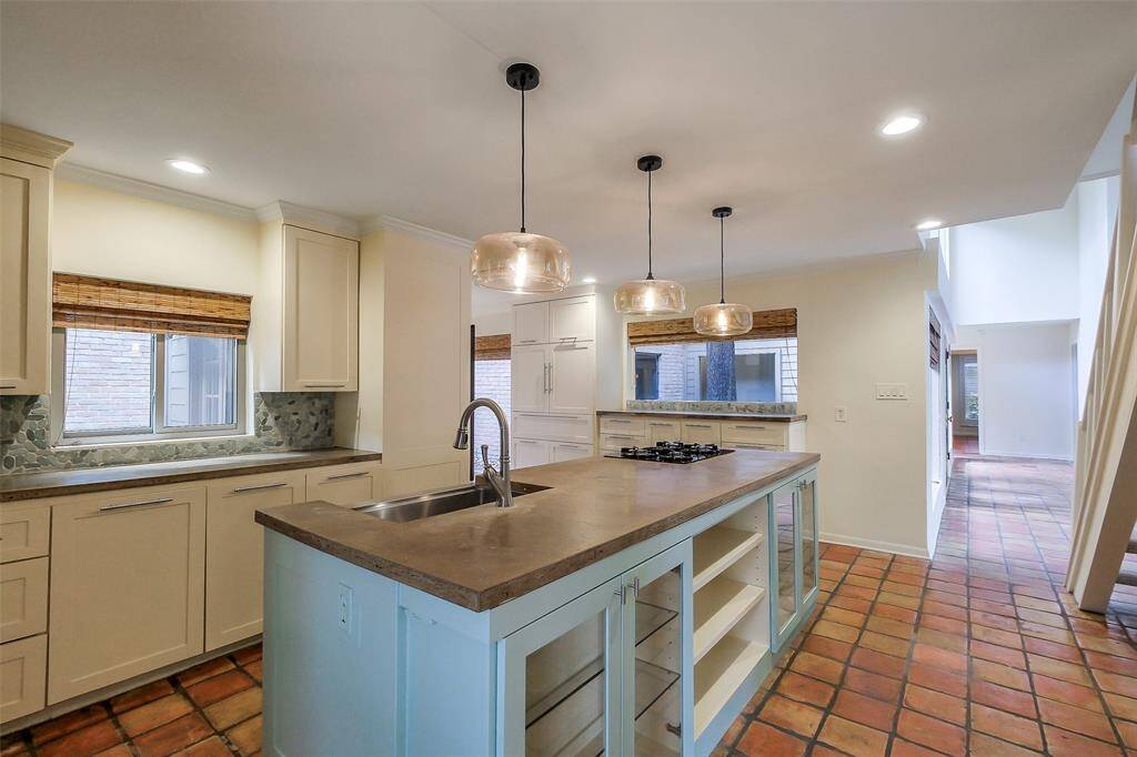 Spacious island kitchen with gas cooktop, double ovens and new cabinetry. Beautiful natural light fills this area of the home.