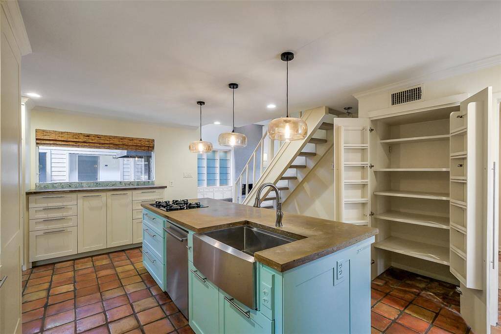 Spacious island kitchen with gas cooktop, double ovens and new cabinetry. Beautiful natural light fills this area of the home. This view shows the recently added custom pantry.