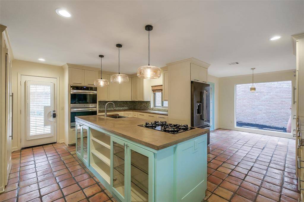 Spacious island kitchen with gas cooktop, double ovens and new cabinetry. Beautiful natural light fills this area of the home. This view shows the kitchen dining area as well.