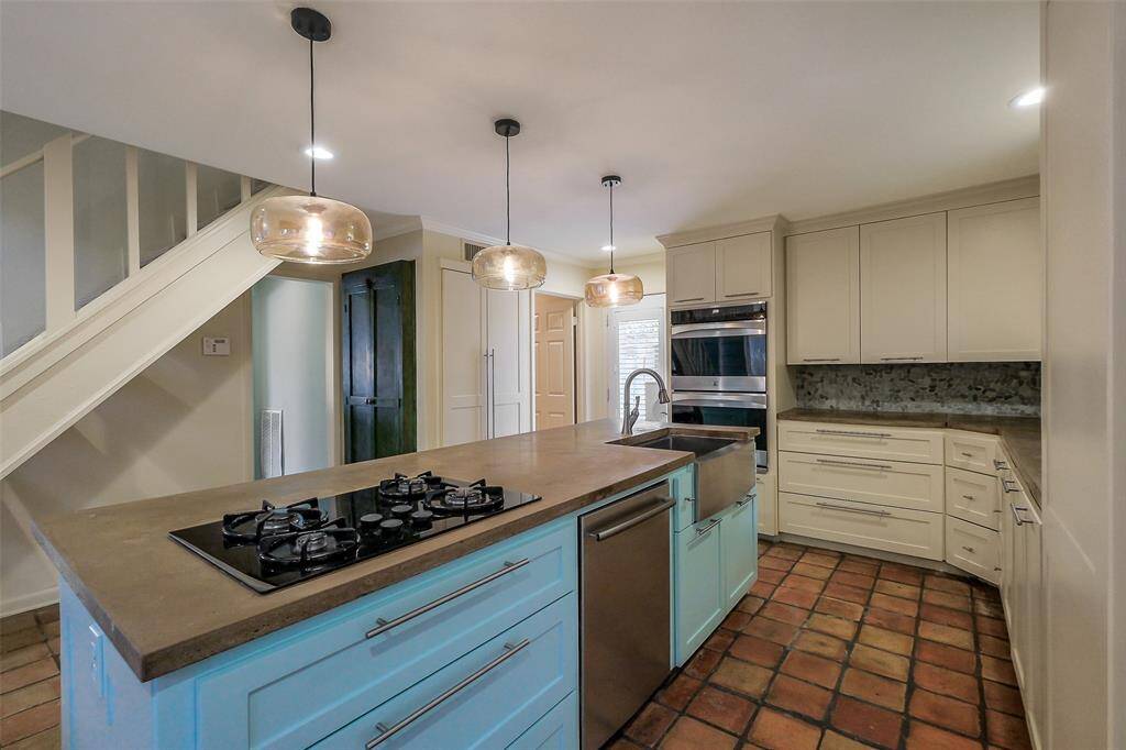 Spacious island kitchen with gas cooktop, double ovens and new cabinetry. Beautiful natural light fills this area of the home.