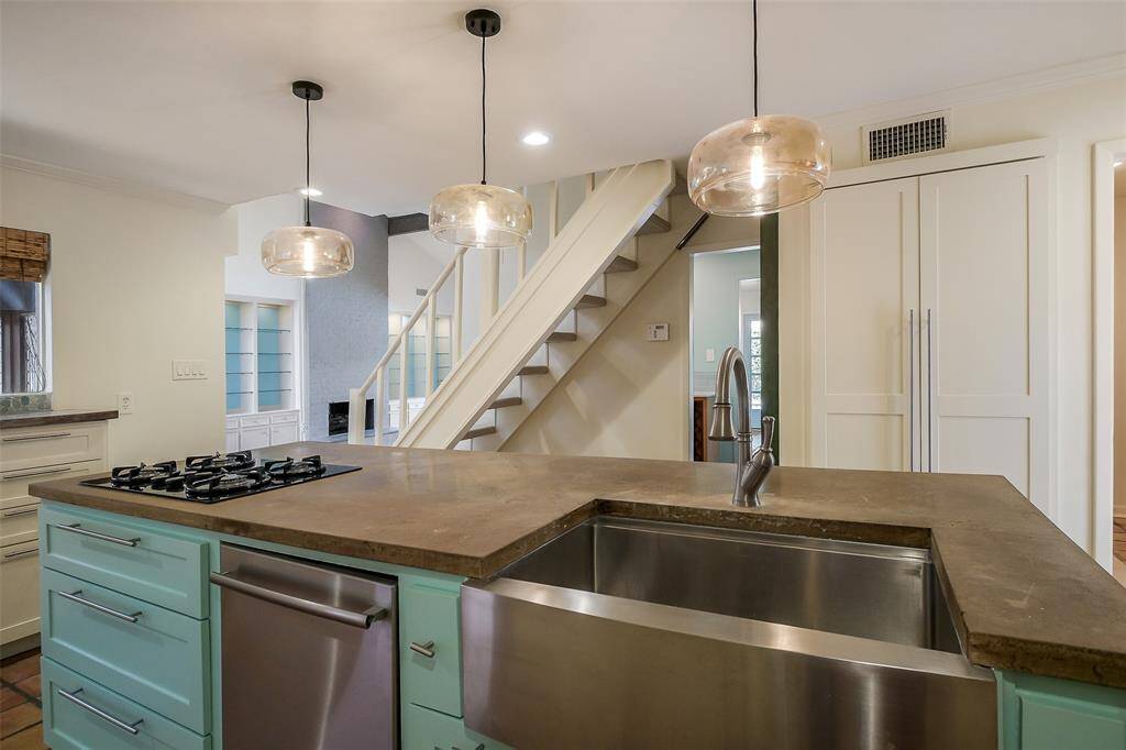 Spacious concrete island kitchen with gas cooktop, double ovens and new cabinetry. Beautiful natural light fills this area of the home.