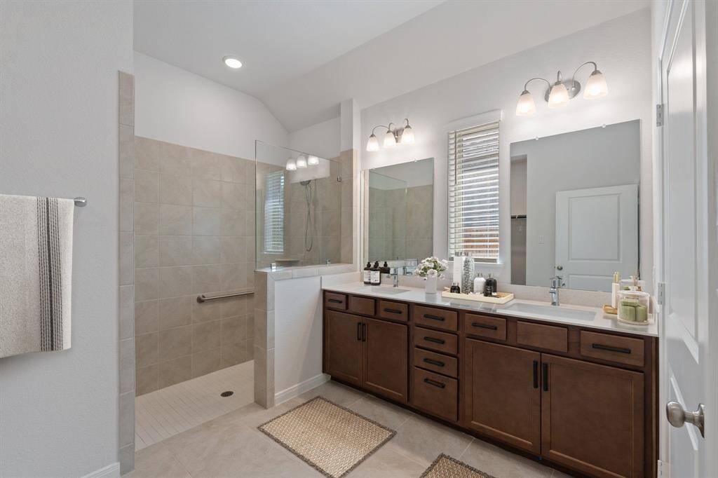 Primary Bathroom with dual sink, super shower with handrails, lots of cabinet storage. (Virtually Staged)